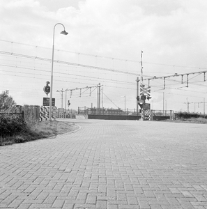 169434 Gezicht op de spoorwegovergang aan de zuidzijde van het N.S.-station Geldermalsen te Geldermalsen.